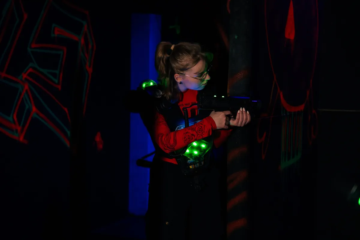 Spielerin mit Lasertag-Weste und Phaser in der Neon-Arena