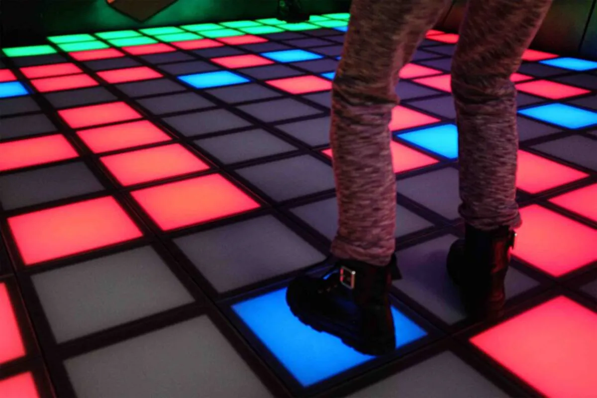 Füße auf einem leuchtenden LED-Boden mit roten, blauen und grünen Kacheln
