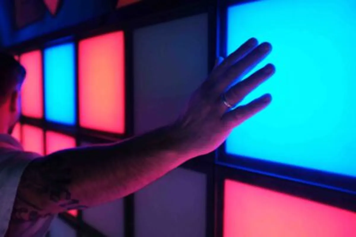 Hand berührt eine leuchtende blaue Platte an der Lightjumper-Wand