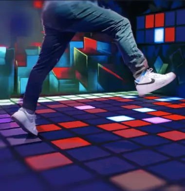 Person auf einem interaktiven LED-Boden mit roten und blauen Quadraten